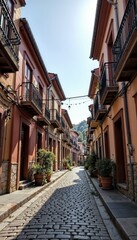 Fototapeta premium A charming cobblestone alley lined with colorful houses and vibrant plants under a clear blue sky 