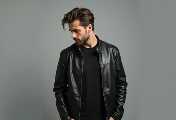 Fototapeta premium A man with a beard wearing a black leather jacket t shirt and jeans.