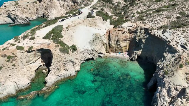 Aerial drone cinematic video of paradise volcanic beach and caves of Tsigrado in island of Milos, Cyclades, Greece
