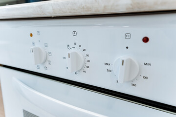 This image shows a closeup of a pristine white oven, highlighting its immaculate design with white knobs and a red light indicator, showcasing modern kitchen aesthetics