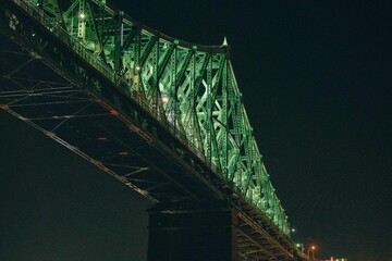 low point of view view of a green suspended bridge as seen from the river in summer at night