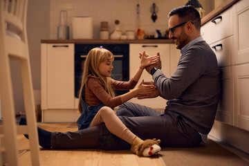 Happy father and daughter playing hand clapping game at home.