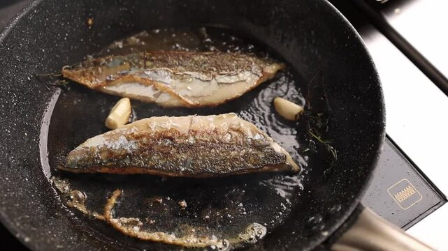 in the kitchen, frying fish in a frying pan