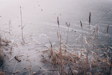 Landscape of blue deep ice lake in winter in daytime, clouds in sky, mountains
