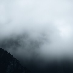 Naklejka premium Close-up, long and wide banner, showcasing a black and white stone mountain in thick fog. The dark gray grunge banner offers space for design.