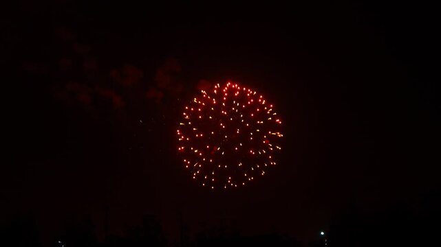 gold red blue sparks scattering fireworks on the black night sky over the city. General plan