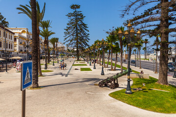 Obraz premium vibrant Mediterranean promenade lined with palm trees, cafes, and historic buildings,
