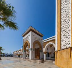 Obraz premium grand mosque with a towering minaret and a symmetrical facade, surrounded by palm trees and a spacious plaza, creating a striking and serene architectural landmark.