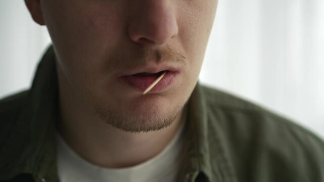 A man uses a toothpick.
A man with a toothpick in his teeth.
The food is stuck in the teeth and the man takes the food out of his teeth.
Dental floss.
Dental care.