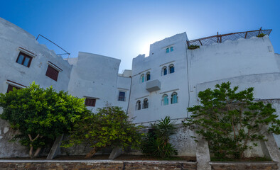 traditional whitewashed building with a charming balcony, nestled amidst a maze of narrow streets and steps, offering a glimpse into the authentic character of a historic Mediterranean city