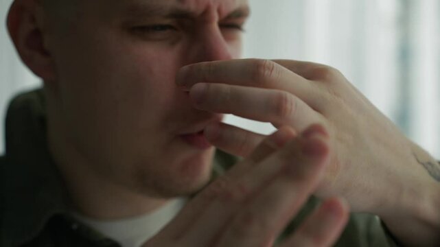 Someone has polluted the air in the room.
The man covers himself and waves his hand because it stinks very strongly.
Unpleasant smell in the room