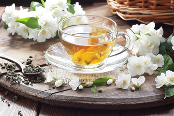 Jasmine herbal tea in a glass cup with flowers on black background, closeup, spring floral drink,...