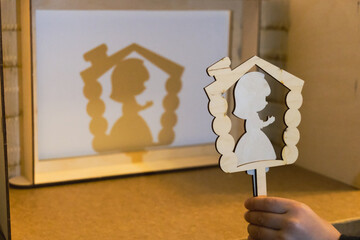 Child is playing shadow theater with a wooden figurine of mouse. Child holds a plywood figurine in...