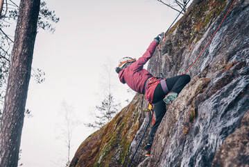 Rock climber climbing high rock wall, extreme sport outside, alpinism equipment