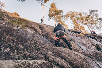 Obraz premium Rock climber climbing high rock wall, extreme sport outside, alpinism equipment