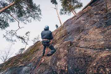 Rock climber climbing high rock wall, extreme sport outside, alpinism equipment