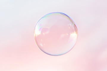 Translucent soap bubble against soft pastel pink background