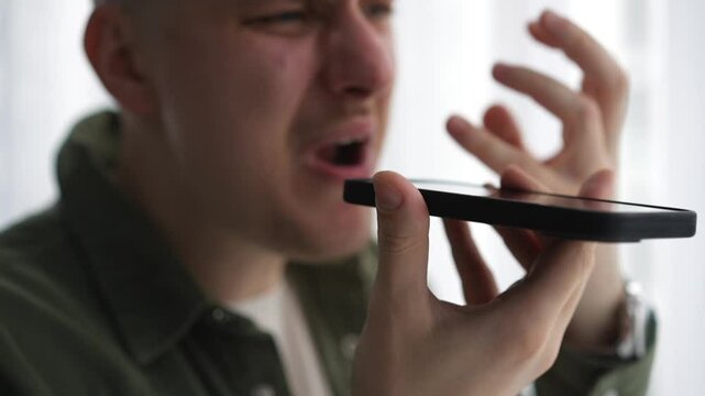 A man with angry facial expressions is talking on the phone.
Emotional conversation on the phone.
A man is talking on speakerphone.
Angry man shouts at his interlocutor
