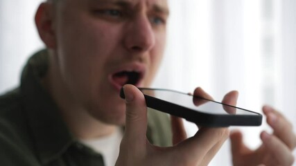 A man with angry facial expressions is talking on the phone.
Emotional conversation on the phone.
A man is talking on speakerphone.
Angry man shouts at his interlocutor