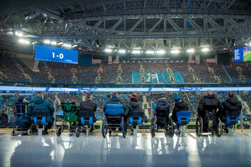 Football match soccer field, fans disabled person sit stands, players run ground
