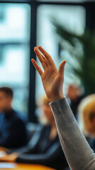Photo Description: An office worker raising their hand to speak during a meeting