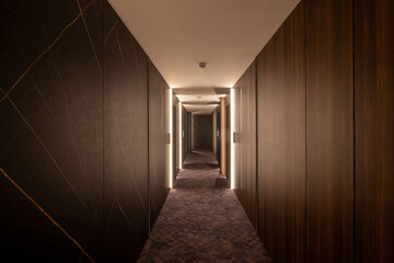 Interior of a long hotel corridor with wooden walls