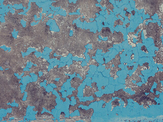 Blue peeling paint on the wall. Old concrete wall with cracked flaking paint. Weathered rough...