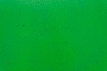 A textured green painted surface with subtle imperfections, rough texture, and small droplets.