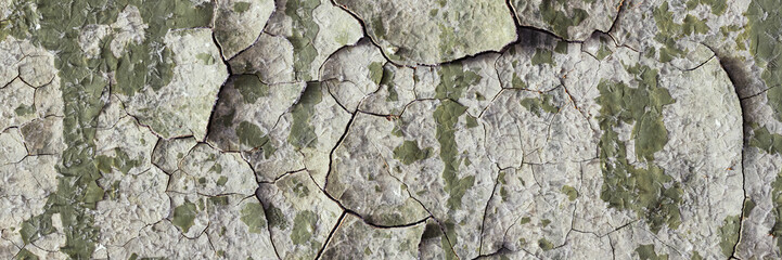Peeling paint on the wall. Panorama of a concrete wall with old cracked flaking paint. Weathered rough painted surface with patterns of cracks and peeling. Grunge texture for wide panoramic background