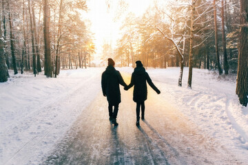 Couple Holding Hands in Winter Wonderland Path Surrounded by Snow-Covered Forest