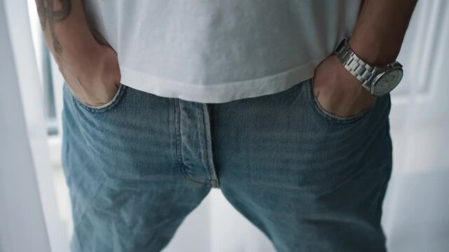 A man tries on pants in a fitting room in a store.
Hands in pockets.
Pants with pockets.
A man hides his hands in his trouser pockets.
Denim pants