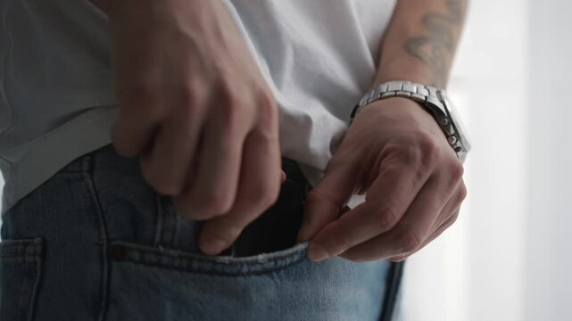 A man in jeans puts his phone in his pocket.
Phone in the pocket of denim pants.
Mobile device in your pocket