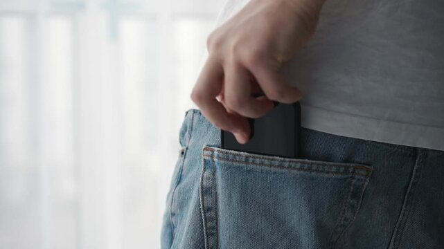 A man in jeans puts his phone in his pocket.
Phone in the pocket of denim pants.
Mobile device in your pocket