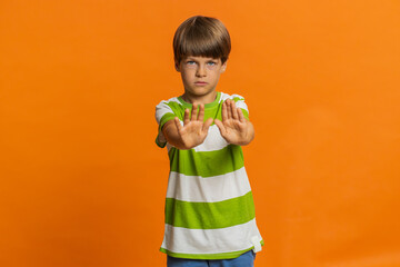 Stop, enough. Preteen child boy kid say no hold hands palms in finish danger gesture, don't want to...
