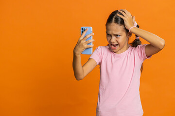 Upset sad preteen child girl kid use smartphone typing browsing, play game, loses, surprised by...