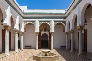 courtyard with a central fountain surrounded by whitewashed walls, arched colonnades, and intricate tiled floors, creating a tranquil oasis within a historic building