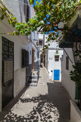 narrow, winding alleyway in a traditional Moroccan medina, with whitewashed buildings, colorful doors, and intricate architectural details, creating a picturesque and authentic scene