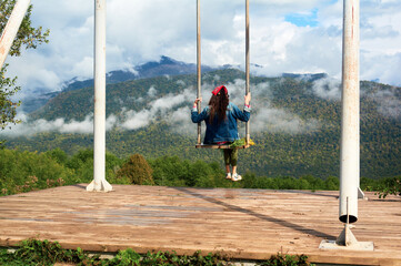 Dream and travel concept, Young beautiful woman happy on swing flying in the sky over stunning mountain view