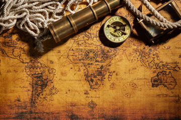 Travel geography background. Old spyglass, rope, vintage compass and magnifying glass on geographical vintage atlas map of the world. Free space for your text