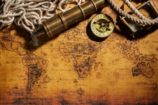 Travel geography background. Old spyglass, rope, vintage compass and magnifying glass on geographical vintage atlas map of the world. Free space for your text