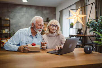 Senior couple excited open a gift while have video call on laptop