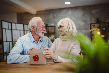 senior husband give gift box with red ribbon to her senior wife