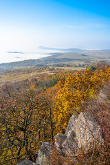 Visitors enjoy a breathtaking autumn view from Laffita Lookout Point, where vibrant foliage contrasts with misty valleys and distant mountains in the Central Bohemian Uplands.