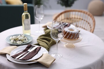 Festive table setting with dishware, desserts, wine and glasses indoors