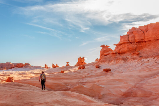 Man hiking among red rock formations in Goblin Valley State Park in Utah.