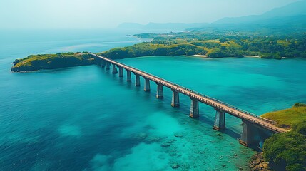 Obraz premium Aerial view of a long bridge connecting two landmasses across a vibrant turquoise ocean.