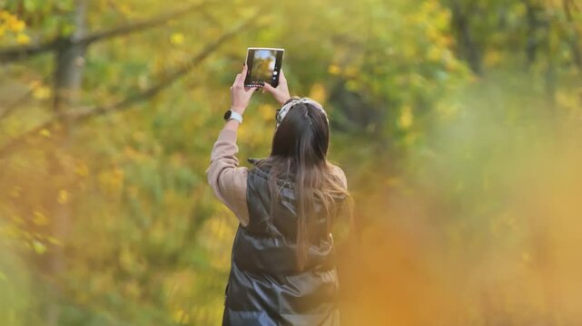 Foldable smartphone in use as woman films serene autumn landscape full of colors
