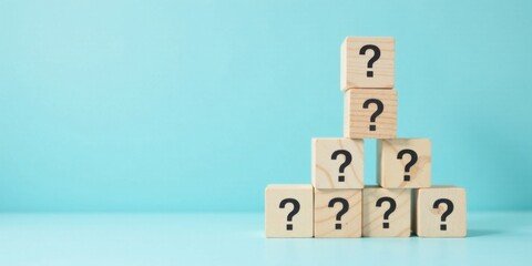Wooden blocks forming a pyramid shape display question marks, symbolizing uncertainty and the search for answers.