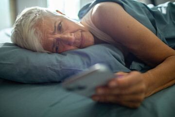 Senior woman using smartphone in bed