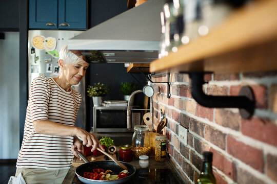 Senior woman cooking healthy meal in modern kitchen